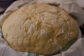 Une boule de pâte à pain levée, prête à être façonnée et cuite, montrant une texture aérée et une surface légèrement farinée, illustrant une étape essentielle de la fabrication du pain maison, typique de la gastronomie corrézienne. 