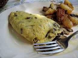 Une omelette aux champignons accompagnée de pommes de terre sautées, servie dans une assiette blanche avec une fourchette, illustrant un plat simple et savoureux de la cuisine maison, élement essentiel de la gastronomie corrézienne. 
